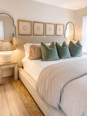 A bedroom with a large bed, a bedside table with a lamp, and a wall with framed pictures. - Remodeled Beachfront-Amazing Location! 
Gated Community. (Destin)