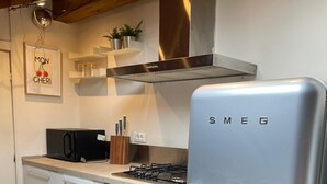 Una cocina con refrigerador de acero inoxidable, horno y microondas. Hay armarios, un lavamanos y una encimera.