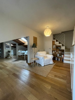 Ein geräumiger Wohnbereich mit einer Couch, einem Esstisch und einer Treppe.