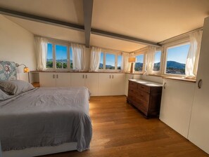 Una camera da letto con un letto, una cassettiera in legno e diverse finestre con tende.