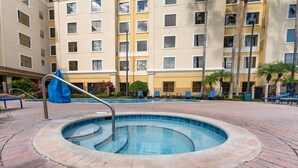 Une piscine de forme circulaire, entourée d’une terrasse en briques.