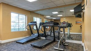 Une salle de sport équipée de tapis de course, d’un vélo elliptique et d’un vélo d’appartement.