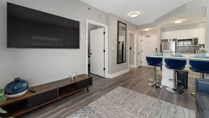 A modern kitchen with white cabinets, a microwave, and a large island with bar stools. - StaySky Suite near Universal & I-Drive (Orlando)