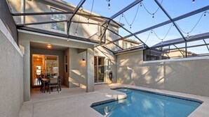 A swimming pool with a glass ceiling, a dining area with chairs, and a view of the sky. - 4BR Storey Lake Home Near Disney with Pool (Kissimmee)