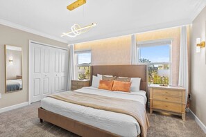 Une chambre à coucher avec un grand lit, des tables de chevet, un miroir et une fenêtre donnant sur un beau paysage.