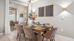 A dining area with a wooden table set for four, surrounded by chairs, with a vase of flowers on the table. - 4BR Storey Lake Home Near Disney with Pool (Kissimmee)