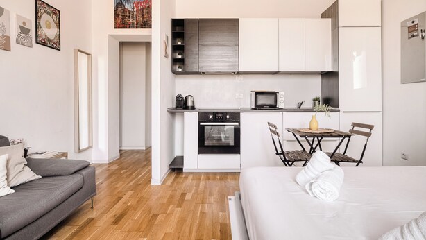 En modern lägenhet med ett litet kök, en matplats, en soffa och en säng.