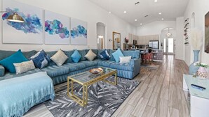 Un salón amplio con un sofá modular, una mesa de centro y obras de arte en las paredes.