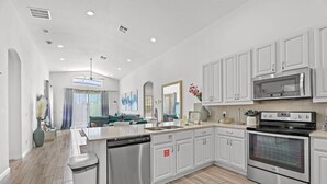 Una cocina moderna con armarios blancos, electrodomésticos de acero inoxidable y una isla central.