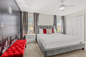 A bedroom with a bed, a bench, a nightstand, a ceiling fan, and a view of the outside. - 4BR Storey Lake Home Near Disney with Pool (Kissimmee)