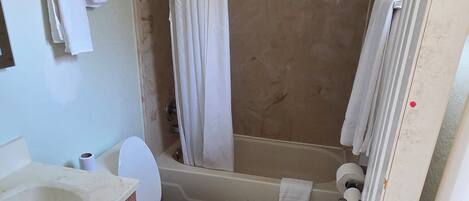 A bathroom with a toilet, sink, shower, and a towel rack.
