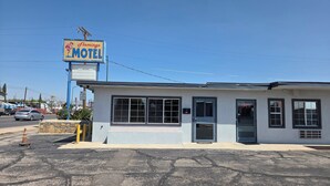 A motel with a signboard, a single entrance door, and a parking lot. - Flamingo Motel (El Paso)