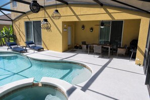 Un espace piscine comprenant des chaises longues, un jacuzzi et une terrasse avec mobilier d’extérieur.