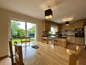 A modern kitchen with wooden cabinets, a central island, and a dining area with a table and chairs.