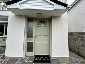 A front door with a small overhang, a doormat, and a number plate. - An Tulan Cleasach Spiddal (Spiddal)