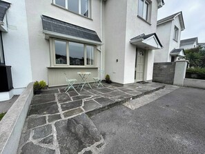 A residential property with a stone-paved driveway, a front door, and a small patio area with a table and chairs. - An Tulan Cleasach Spiddal (Spiddal)