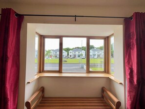 Una habitación con ventana saliente con vistas a un barrio residencial.