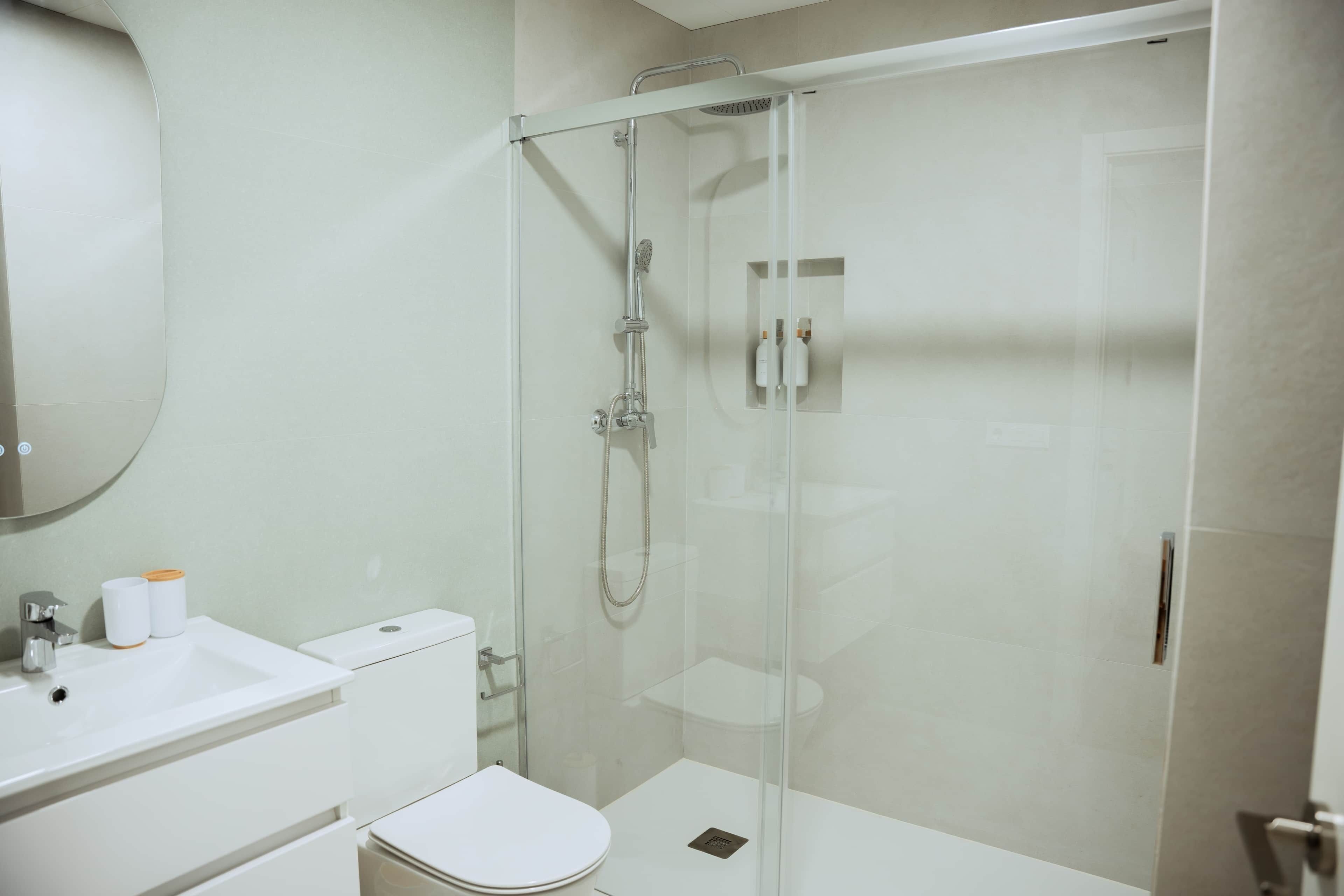 A modern bathroom with a glass-enclosed shower, a white sink, and a toilet.