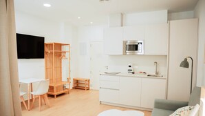 Ein moderner, gut beleuchteter Raum mit Küchenzeile, einem Essbereich mit Tisch und Stühlen sowie einer Sitzecke mit einer Couch.