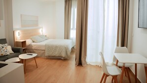Ein modernes Hotelzimmer mit Bett, einer Couch, einem Esstisch und einem Sessel.
