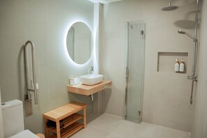 Ein modernes Badezimmer mit einer gläsernen Duschkabine, einem Holzwaschtisch, einem runden Spiegel und einer Toilette.