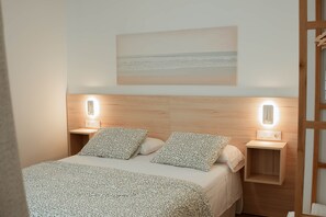 A neatly arranged bedroom with a bed, two bedside tables, and a wall-mounted light fixture. - Olea Suites Conil · 5 (Conil de la Frontera)