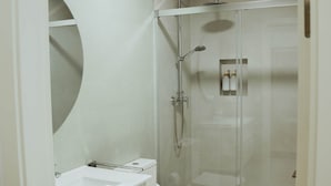 A modern bathroom with a glass-enclosed shower, a white sink, and a toilet. - Olea Suites Conil · 2 (Conil de la Frontera)