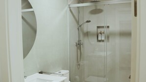 A modern bathroom with a glass-enclosed shower, a white sink, and a toilet. - Olea Suites Conil · 3 (Conil de la Frontera)