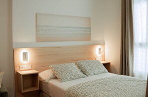 Ein Hotelzimmer mit einem Bett, zwei Nachttischen, einer Wandleuchte und einem Gemälde über dem Bett.