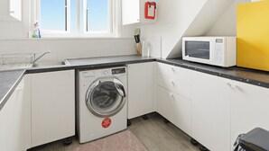A compact kitchen with a washing machine, a microwave, and a sink. - Park View En-Suite I Egham station (1 miunte walk) (Egham)