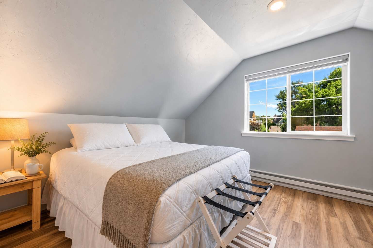 A bedroom with a bed, a nightstand, a lamp, a window, and a ceiling fan.