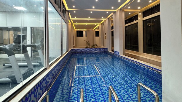 An indoor swimming pool with blue patterned tiles, metal handrails, and a ceiling with recessed lighting. - 2 BR SLEEPS 6 PAX INDOOR POOL, GYM AND BEAUTIFUL NAIROBI CITY VIEWS (Nairobi)