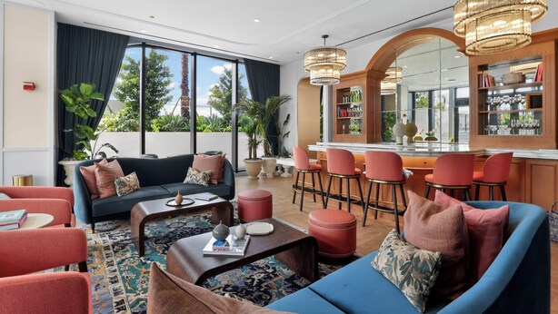 En modern hotellobby med en sittgrupp, en bar och stora fönster som ger utsikt över omgivningarna.