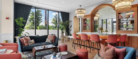 En modern hotellobby med en sittgrupp, en bar och stora fönster som ger utsikt över omgivningarna.
