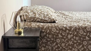 Ein Schlafzimmer mit einem Bett, einem Nachttisch mit Lampe und einem Wandregal.
