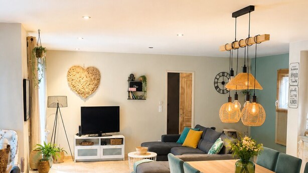 A modern living room with a sofa, TV, dining table, and chairs.