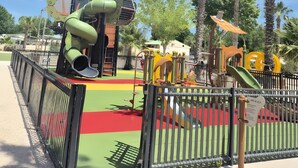 Ein Spielplatz mit Rutsche, Klettergeräten und einem eingezäunten Bereich.