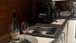 A compact kitchen with a microwave, coffee maker, and wine glasses on the counter. - Gortin Glen Forest Cabin, Sleeps 7 With Parking (Omagh)