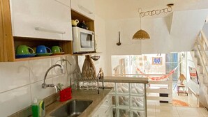 Cuina amb armaris blancs, microones, rentapelats i fogó.