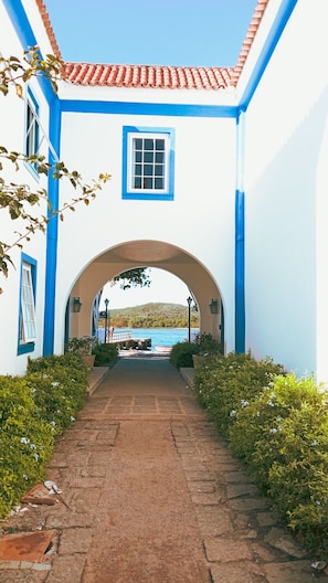 A pathway leading to a building with a tiled roof and a window. - Complete house with 2 bedrooms / Close to everything (Cabo Frio)