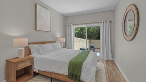 Een slaapkamer met een bed, nachtkastjes, een spiegel en uitzicht op het groen.