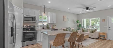 A modern kitchen with white cabinets, stainless steel appliances, and a central island with bar stools.