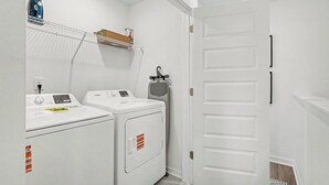 A laundry room with two washing machines, a drying rack, and a small shelf with items. - Grant & Groove: Where timeless design meets the rhythm of ATL. (Atlanta)