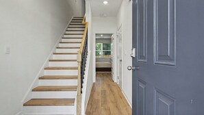 A staircase with wooden steps and a handrail, leading to a room with a door. - Grant & Groove: Where timeless design meets the rhythm of ATL. (Atlanta)