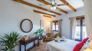 A bedroom with a bed, two chairs, a wooden ceiling, a mirror, a window with curtains, and a potted plant. - Country House in Gaucin (Gaucín)