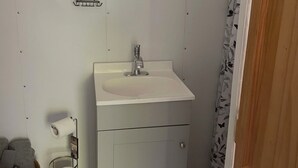 Un baño con lavamanos, espejo y inodoro blancos.