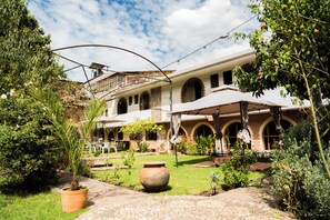 Un patio con un edificio que tiene ventanas de arco y un área de patio techada.