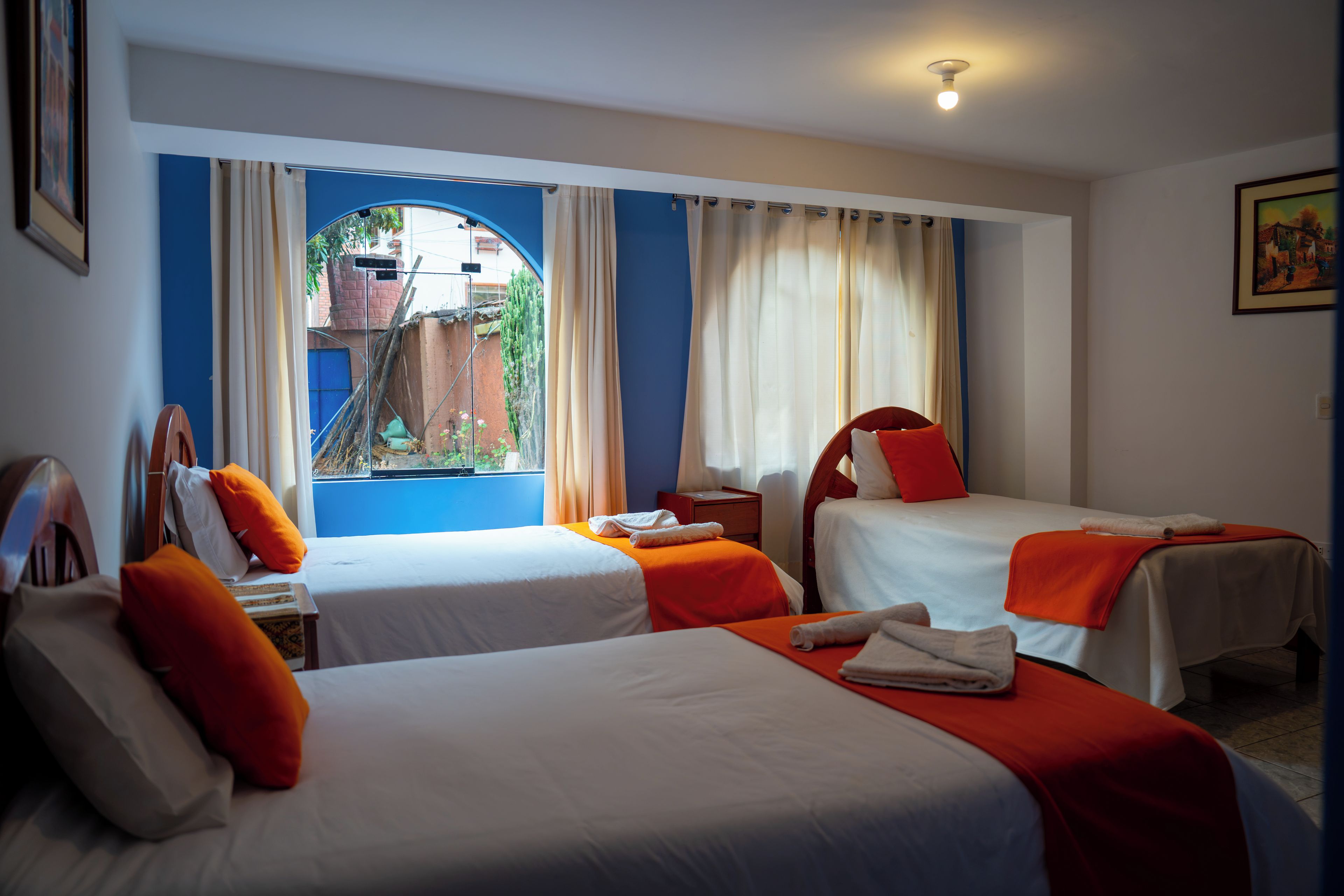 Habitación de hotel con dos camas, una ventana con cortinas, un escritorio y una silla.