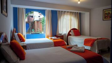 Habitación de hotel con dos camas, una ventana con cortinas, un escritorio y una silla.