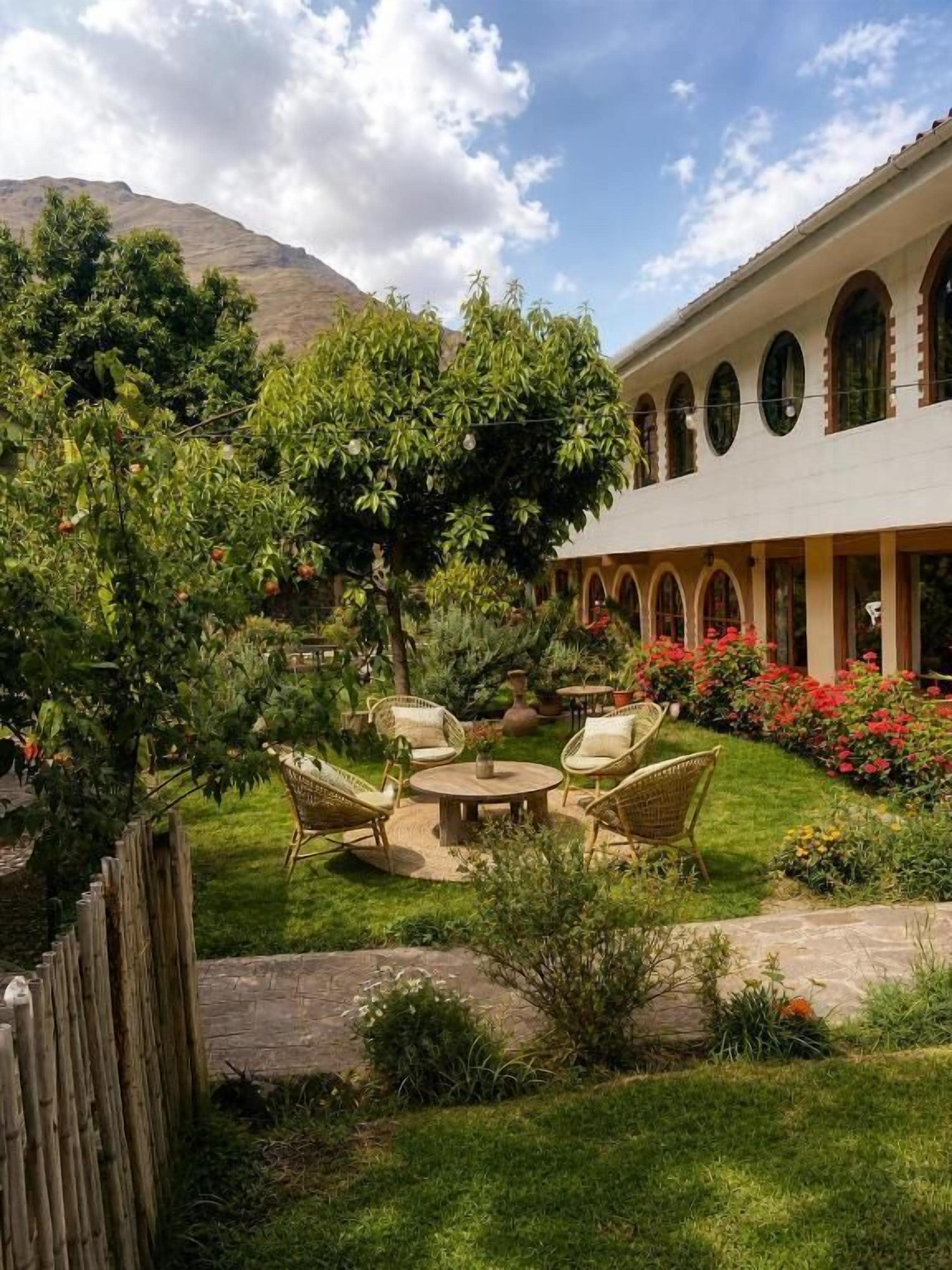 A courtyard with outdoor seating, a wooden fence, and a building with arched windows.